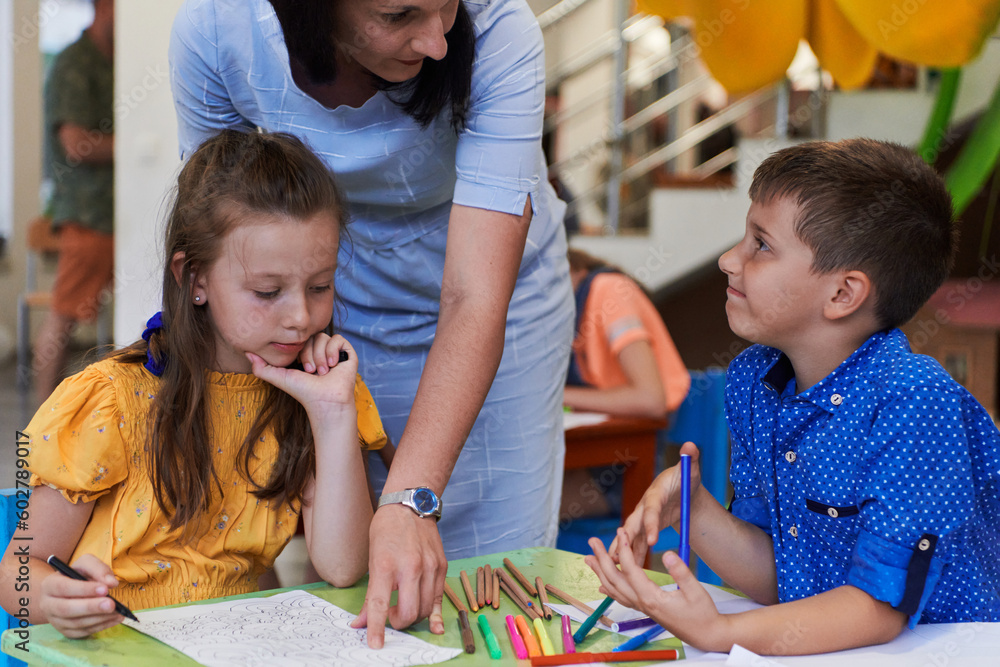 Obraz premium Creative kids during an art class in a daycare center or elementary school classroom drawing with female teacher.