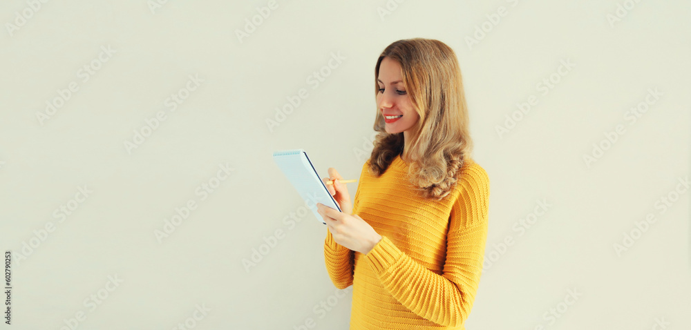 Portrait of young caucasian woman writing down memories in notebook diary on gray background Portrait of young caucasian woman writing down memories in notebook diary on gray background