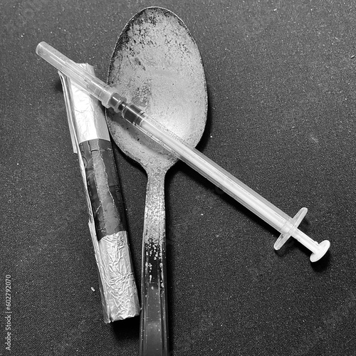 Tools for heroin and drug use. Spoon, syringe and blowtorch for smoking narcotic substances. Items for cocaine consumption. Image with neutral background.
