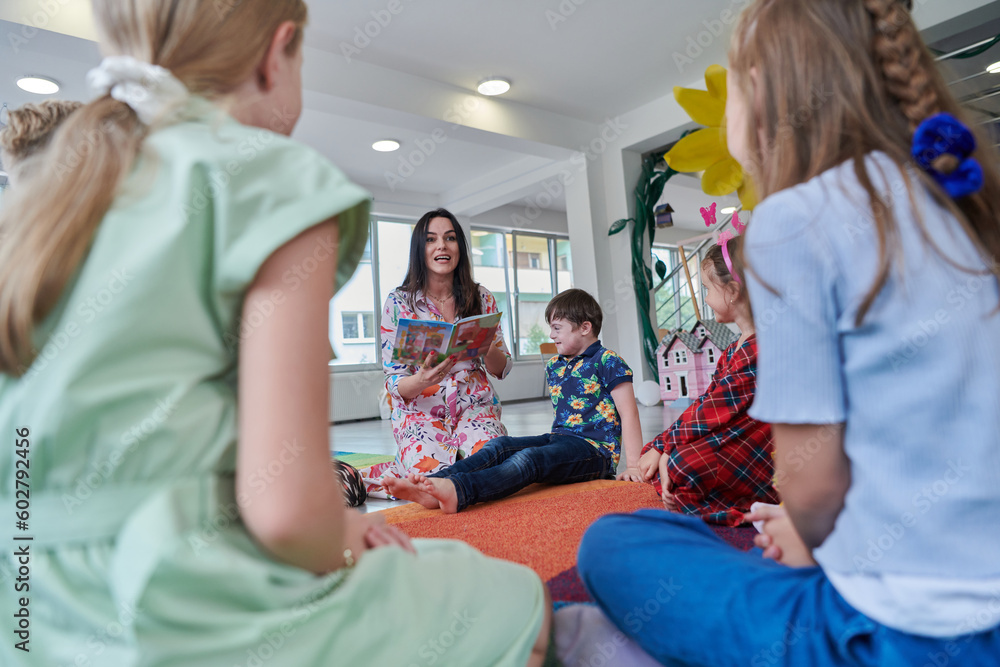 Obraz premium Reading time in an elementary school or kindergarten, a teacher reading a book to children in an elementary school or kindergarten. The concept of pre-school education. Selective focus