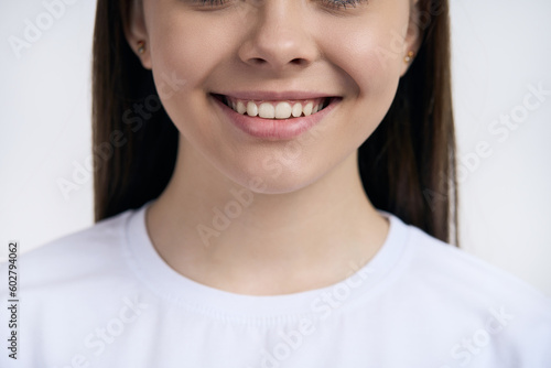 Cropped view face of teenage girl smiling with beautiful toothy smile, isolated on white background