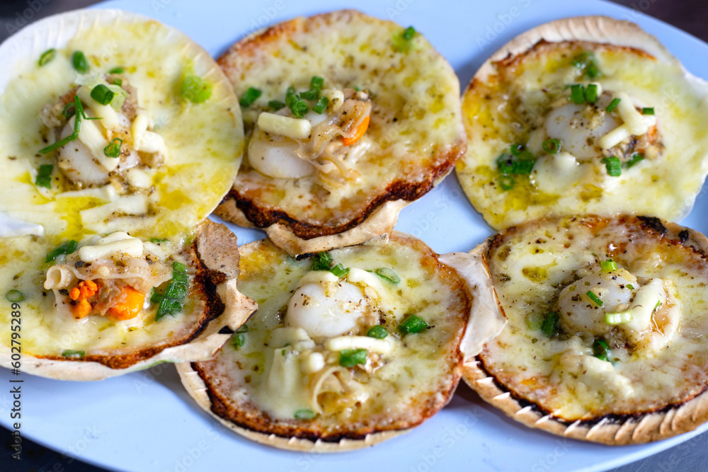 Grilled scallops shell with butter and garlic on white plate Grilled scallops shell with butter and garlic on white plate