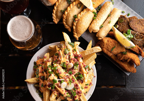 plate of fries and plate of empanadas milanesas and tequenos with beer photo