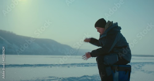 catching fish in iced river in wintertime, adult man hooking fish by rod, ice fishing, 4K, Prores
