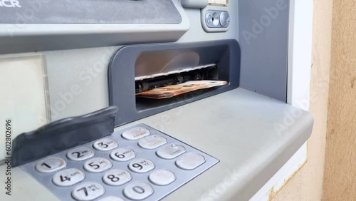 Woman withdrawing cash money banknotes from an automated atm bancomat machine,euro bills currency