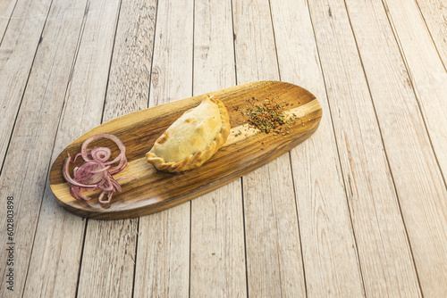 A delicious unit of empanada stuffed with chicken with red onion