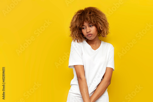 Photos young insecure curly american girl is sad and bored over yellow isolated backgro