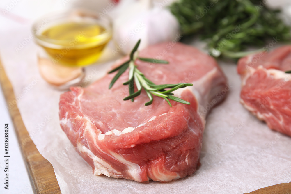 Fresh raw meat with rosemary on wooden board, closeup Fresh raw meat with rosemary on wooden board, closeup