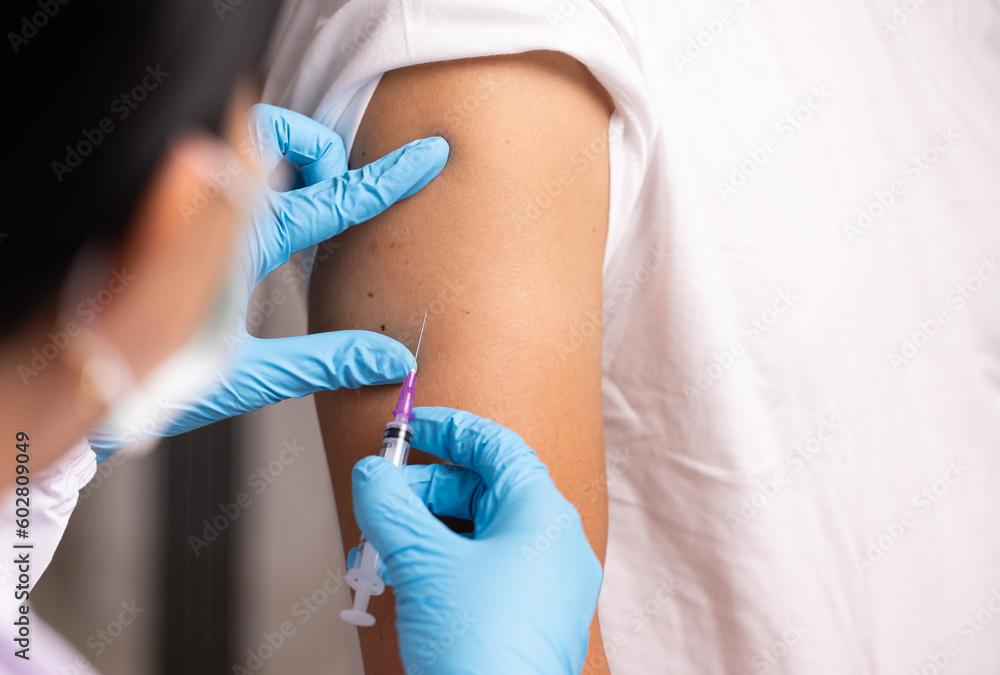 Fototapeta premium Doctor hand in blue gloves holding influenza vaccine for prevention human.Nurse holding syringe make injection in shoulder of patient in hospital.Covid-19 or coronavirus vaccine.