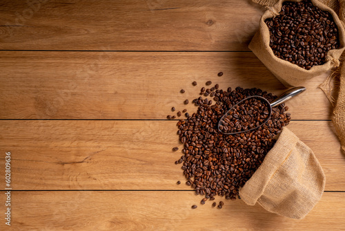 The picture of coffee beans stacked together on a wooden floor in a warm, light atmosphere, on a dark background, with copy space.
