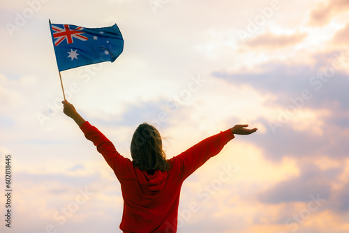 Woman Waving the Flag of Australia on the Sky. Australian girl holding national flag celebrating January 26th 
 photo