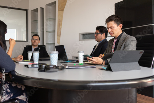 Quadro su tela confused young man looking at his phone distracted while being in a serious work