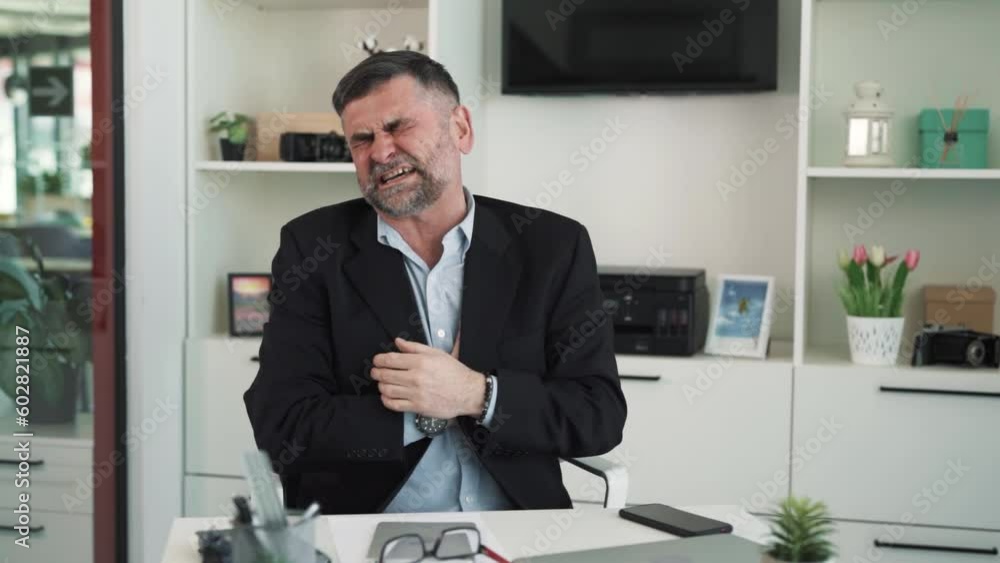 An elderly man sits at the table holding his chest, complains of feeling unwell and health problems An elderly man sits at the table holding his chest, complains of feeling unwell and health problems