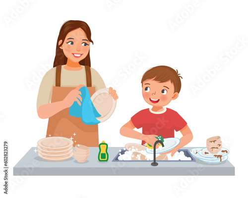 Cute little boy helping mother washing dishes in the kitchen doing housework chores at home