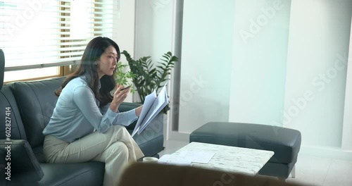 사무실에 출근해서 소파에 앉아 업무 문서를 보는 여성 리더