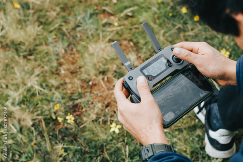 Photograph of a man's hands holding the remote control of a Drone (Drone Operator). Technology concept