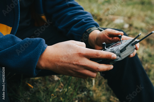 Photograph of a man's hands holding the remote control of a Drone (Drone Operator). Technology concept
