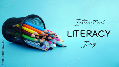 Colored pencil spilled from the case with torn paper incription of world literacy day. photo