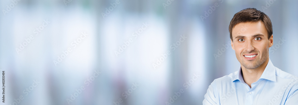 Wide banner image of young businessman in confident shirt cloth, crossed arms, on blurred office background. Business concept. Smiling man at studio photo. Copy space ad text area. Wide banner image of young businessman in confident shirt cloth, crossed arms, on blurred office background. Business concept. Smiling man at studio photo. Copy space ad text area.