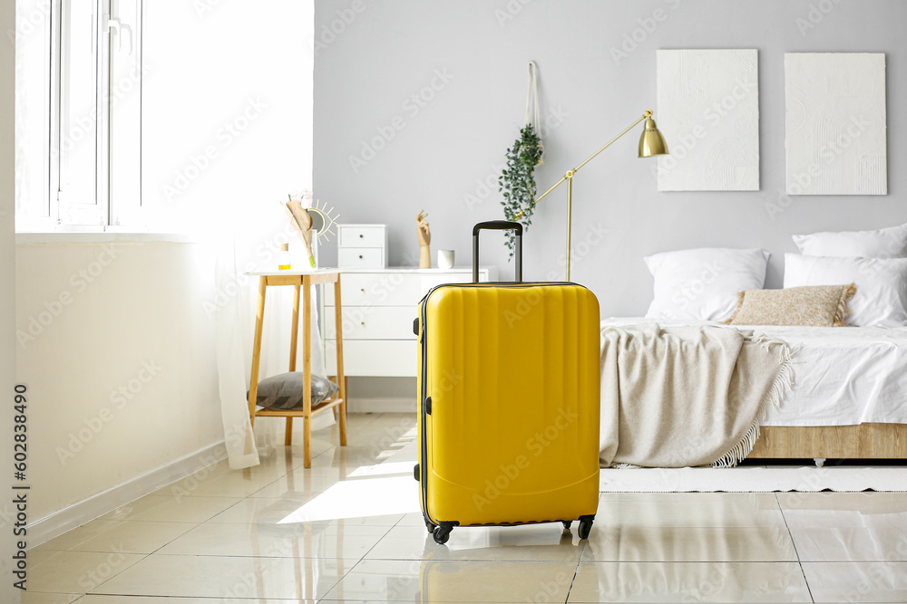 Yellow suitcase in light bedroom - obrazy, fototapety, plakaty 