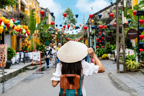 Fotografie Carefree Asian tourist woman wearing Non La (traditional Vietnamese hat) enjoy sightseeing in Hoi An old town Vietnam