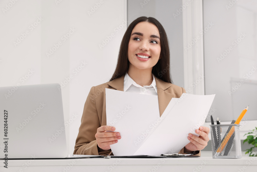 Young female intern working with laptop at table in office Young female intern working with laptop at table in office