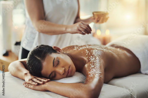 Woman, sleeping and relax in salt scrub massage at spa for skincare, exfoliation or body treatment. Calm female asleep or resting in relaxation for back therapy, health or zen with masseuse at salon photo