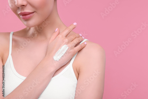Woman with smear of body cream on her hand against pink background  closeup. Space for text