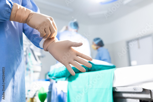 Midsection of surgeon putting on surgical gloves in operating theatre, copy space