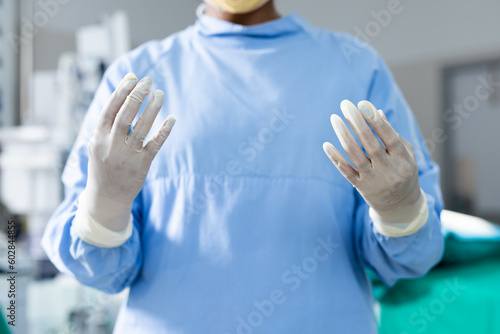 Midsection of surgeon wearing surgical gown and gloves in operating theatre