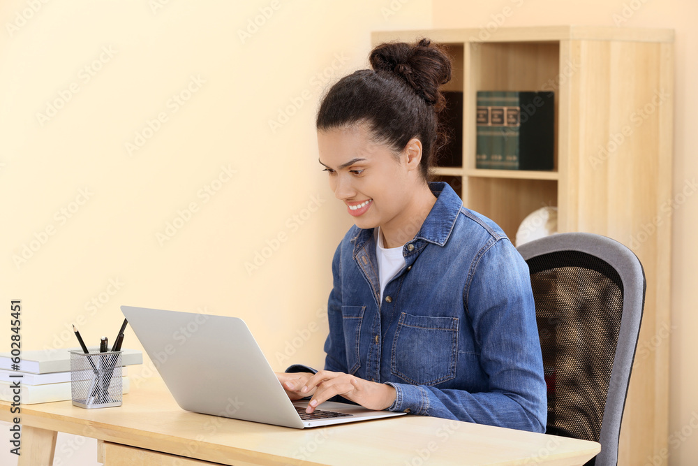 African American woman typing on laptop at wooden table indoors