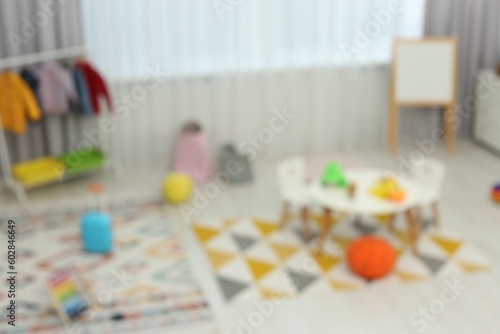 Blurred view of child`s playroom with different toys and furniture. Stylish kindergarten interior