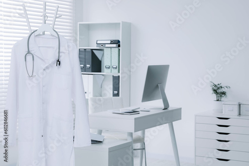 White doctor's gown and stethoscope hanging on rack in clinic © New Africa
