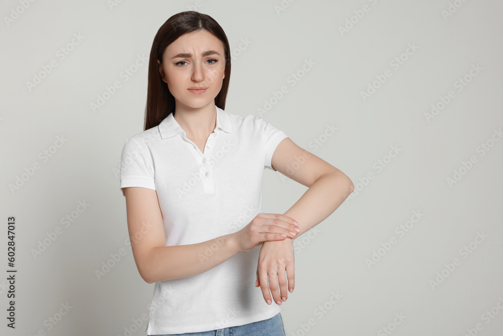 Young woman suffering from pain in her hand on light grey background, space for text. Arthritis symptoms Young woman suffering from pain in her hand on light grey background, space for text. Arthritis symptoms