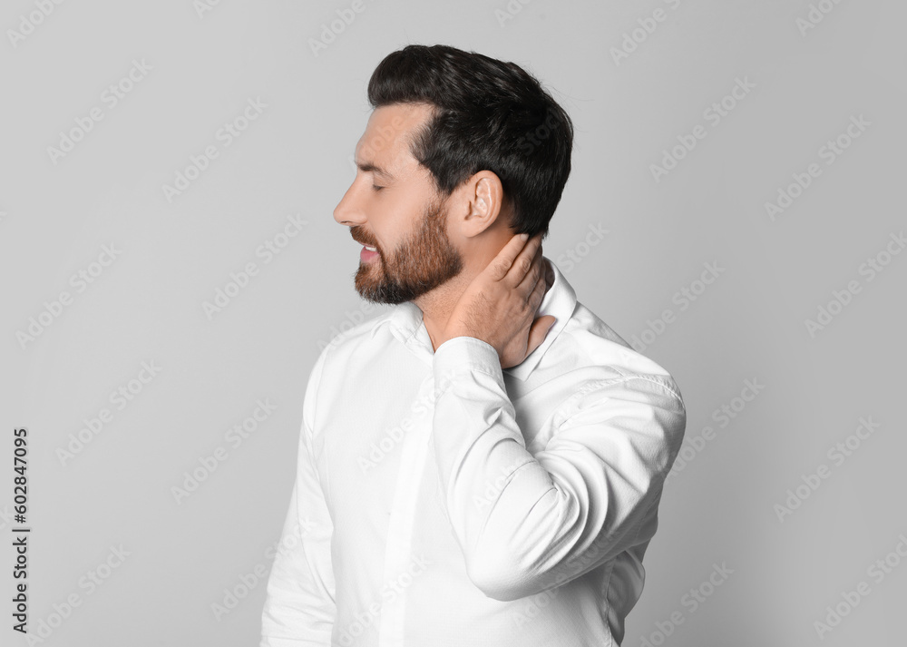 Man suffering from pain in his neck on light background. Arthritis symptoms Man suffering from pain in his neck on light background. Arthritis symptoms