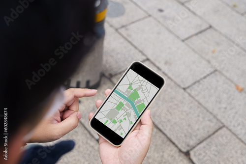 Woman with baggage in downtown city street searching location in map application online on smart phone using GPS navigating.