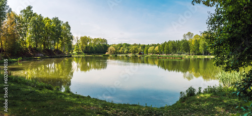 Small lake located in park in Siemianowice Slaskie, Silesia, Poland. Natural coastline covered with grass. Tranquil water surface with reflecting plants during the springtime. Pheasantry, Siemianowice © p  a  t  r  i  c  k