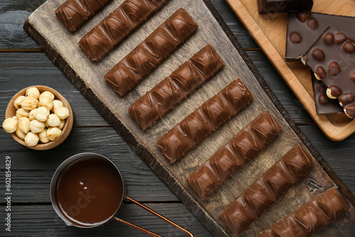 Flat lay composition with sweet tasty chocolate bars and nuts on wooden table