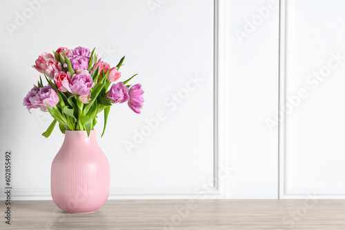 Beautiful bouquet of colorful tulip flowers on floor near white wall, space for text