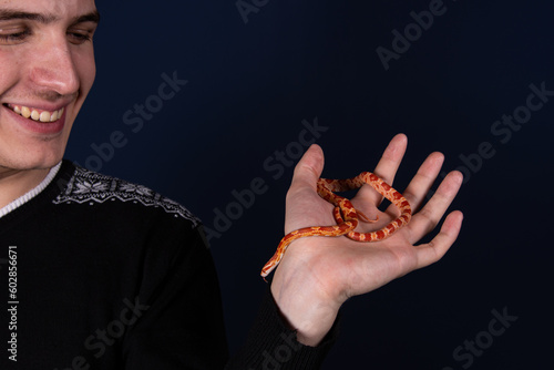 A man holds a small snake in his hands.