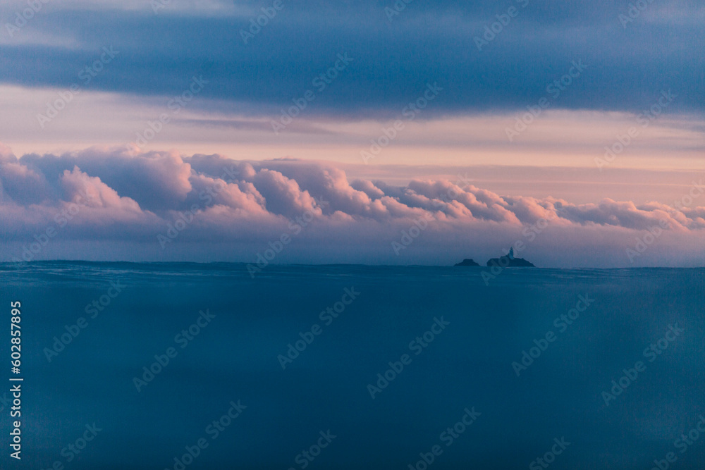 Godrevy lighthouse  at sunrise with beautiful pink clouds.