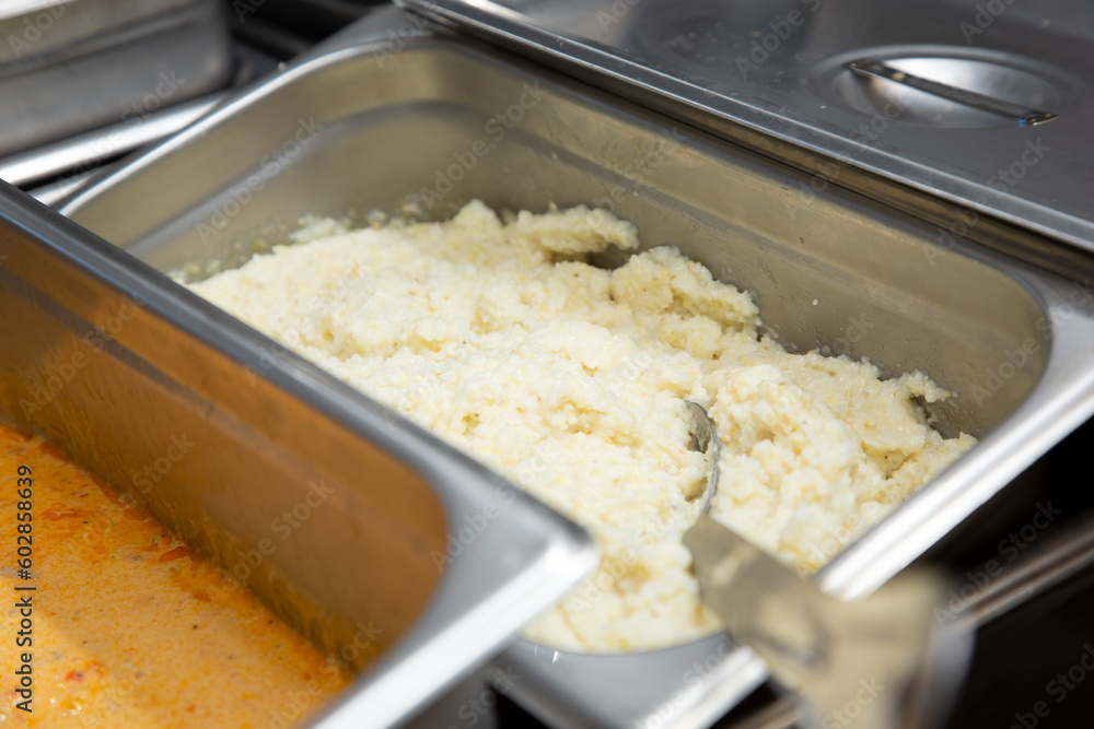 A view of a steamer tray full of grits, seen in a restaurant kitchen setting. A view of a steamer tray full of grits, seen in a restaurant kitchen setting.