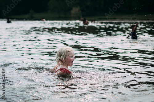 Laughing child swimming in lake on summer evening