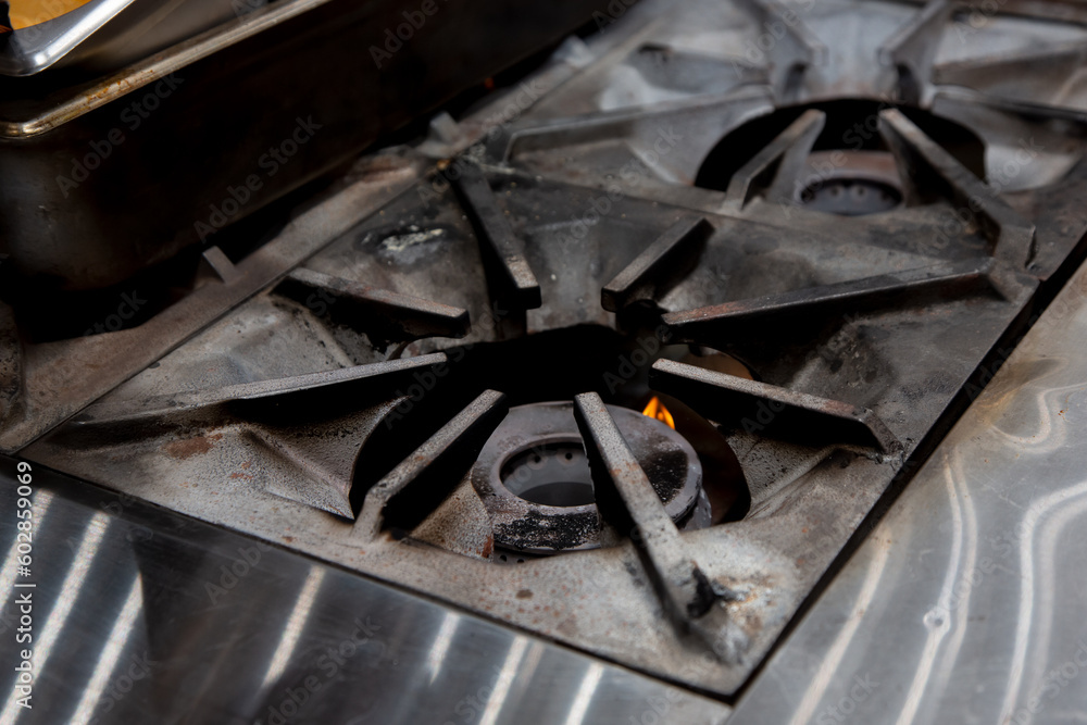 A view of a restaurant kitchen stove area, featuring the burners. A view of a restaurant kitchen stove area, featuring the burners.
