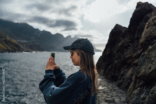 Young tourist taking photos of the landscape with her mobile phone