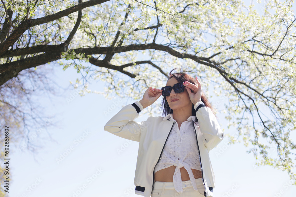A woman poses against a background of flowering branches and the A woman poses against a background of flowering branches and the
