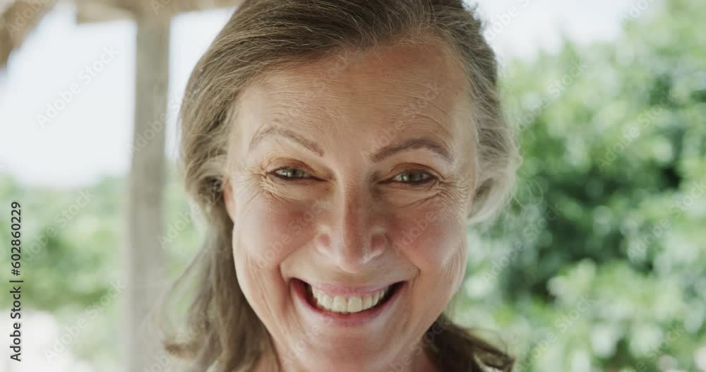 Portrait of happy senior caucasian woman smiling on beach, in slow motion Portrait of happy senior caucasian woman smiling on beach, in slow motion