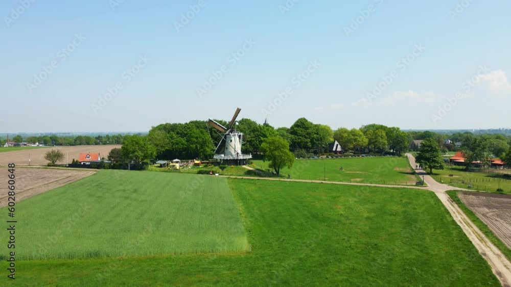 Beautiful classic windmill spinning in a Dutch rural landscape. The drone pulls back and reveals stunning green meadows