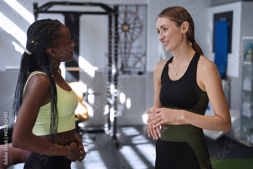 Two sporty women talking in a fitness gym. Sports concept.