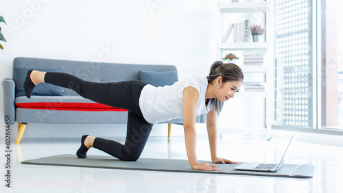 Asian healthy fit slim sexy female sporty athlete model friend in sportwear and leggings laying down planking on yoga mat together watching online streaming workout lesson via laptop computer